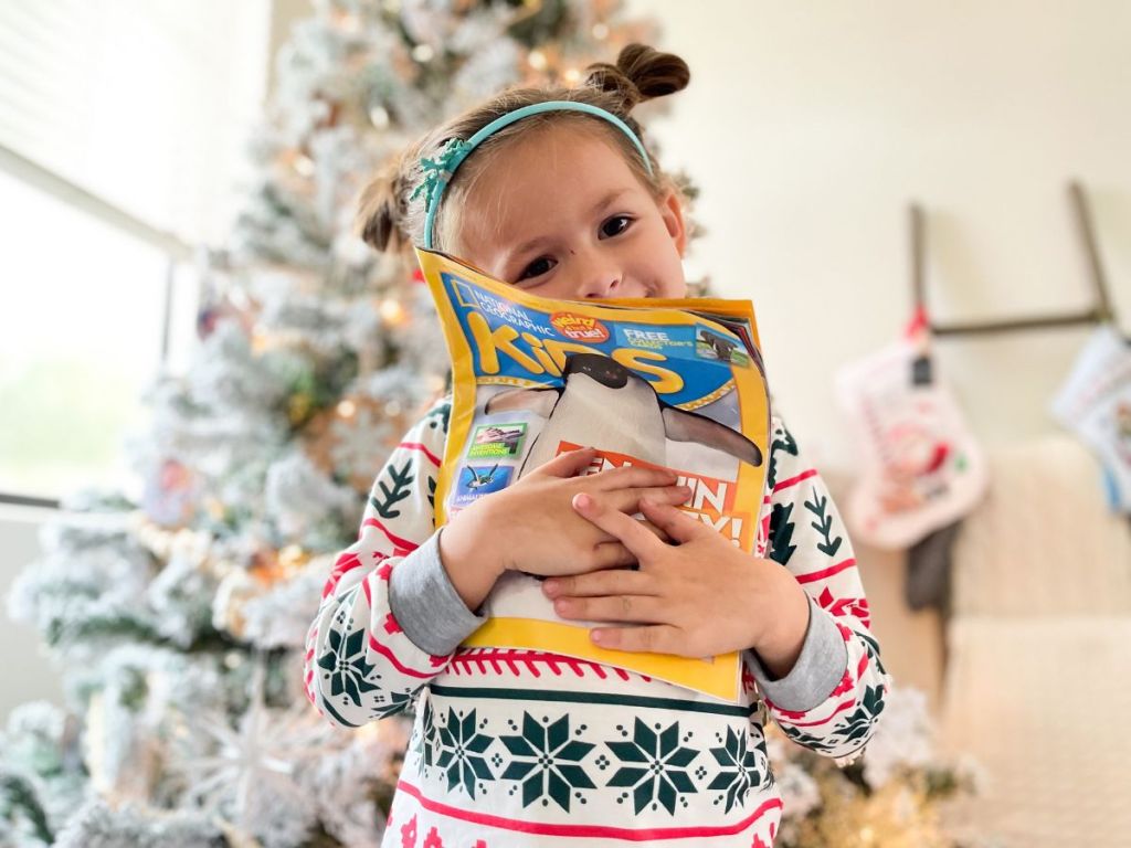 little girl hugging a Nat Geo Kids magazine