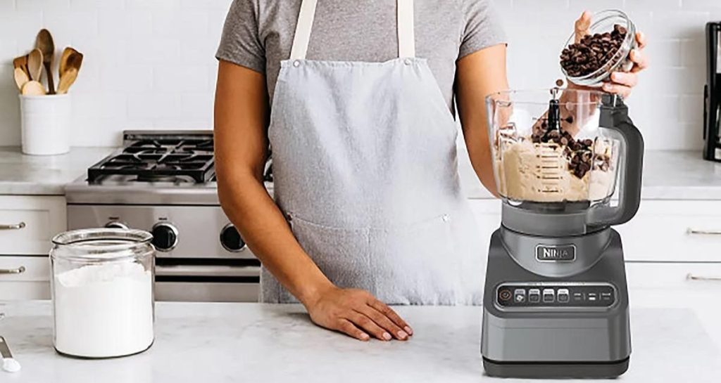 woman using ninja food processor in kitchen counter