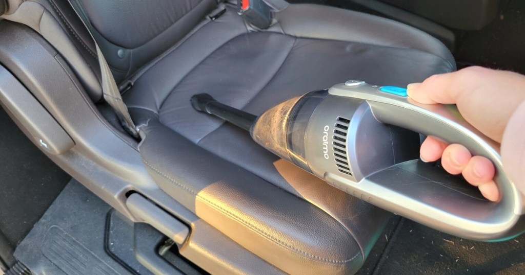 Person vacuuming the seat of a car