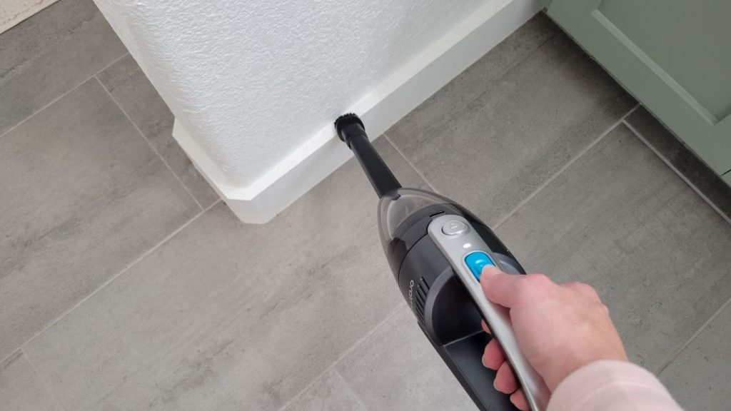 Person vacuuming baseboards in a home