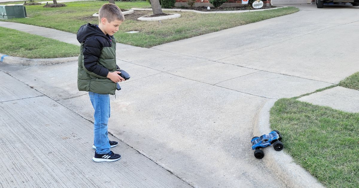 boy using blue Remote Controlled Car in street