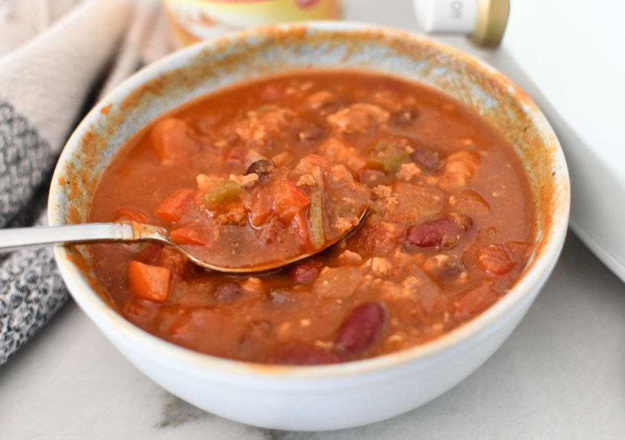 A bowl of pumpkin chili on a counter with a spoon