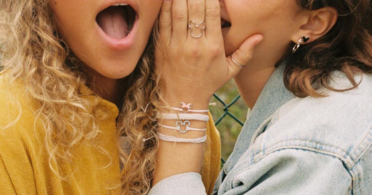 two girls sahring a secret wearing pura vida bracelets and rings