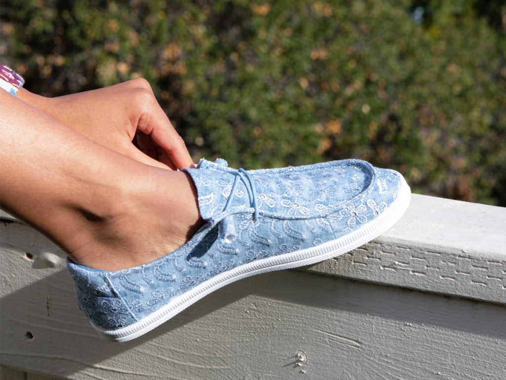 person putting on blue pair of rocket dog sneakers