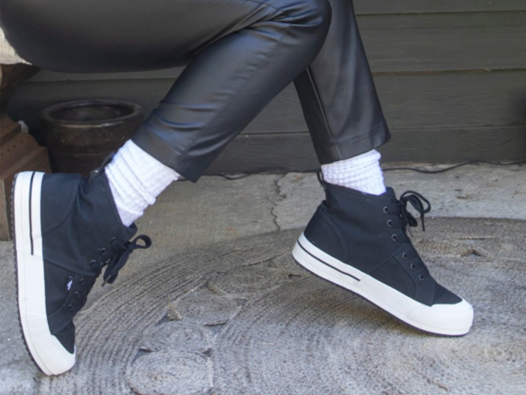 person wearing leather pants and black high top sneakers