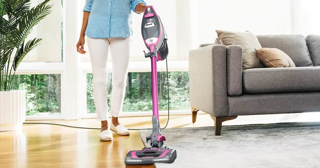 woman using pink and grey shark stick vacuum