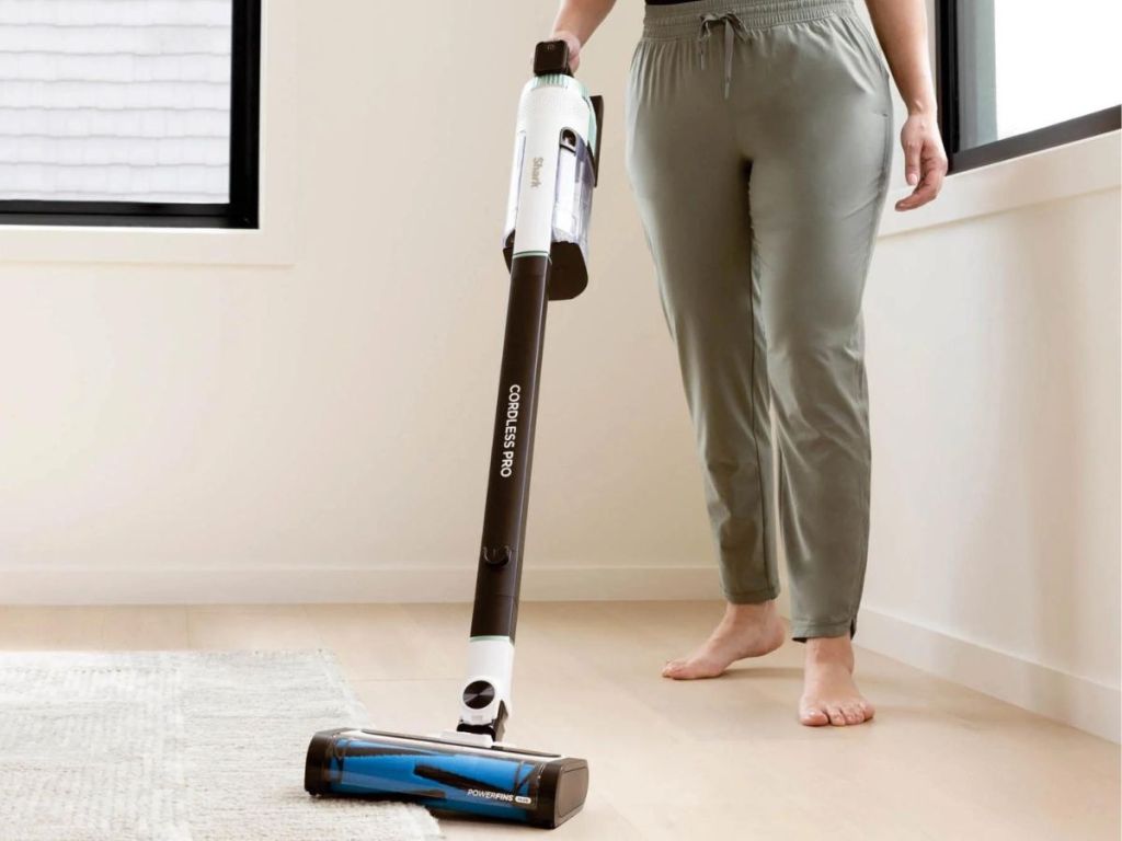 A woman using a Shark cordless vacuum