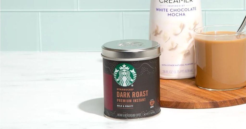 a can of starbucks instant dark roast coffee with a bottle of flavored creamer and a cup of coffee