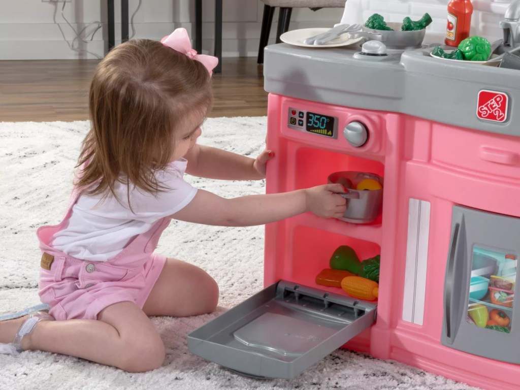 little girl playing with Step 2 Play Kitchen in pink