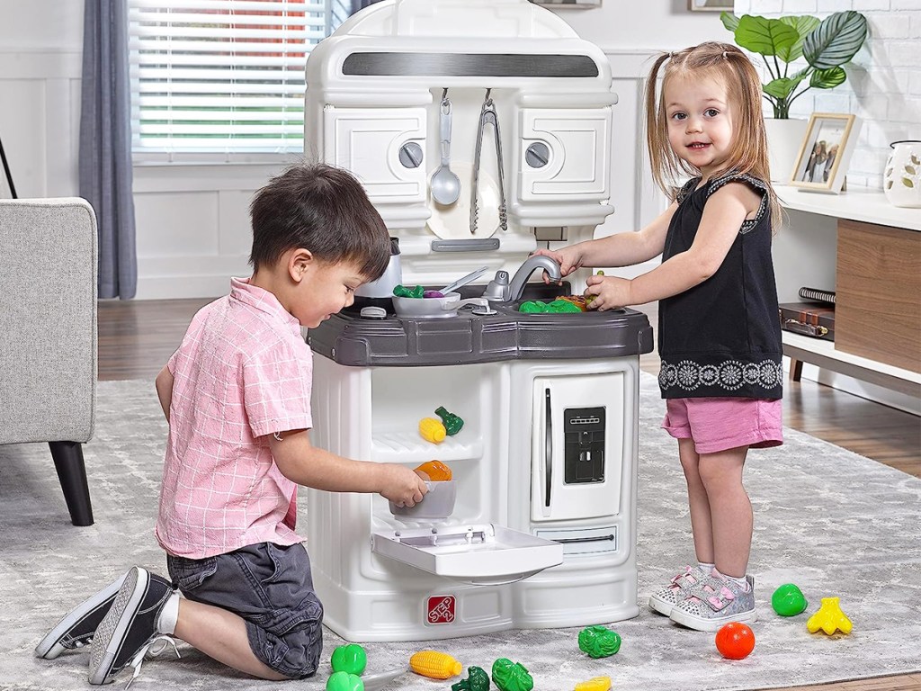 A play kitchen with two kids in it