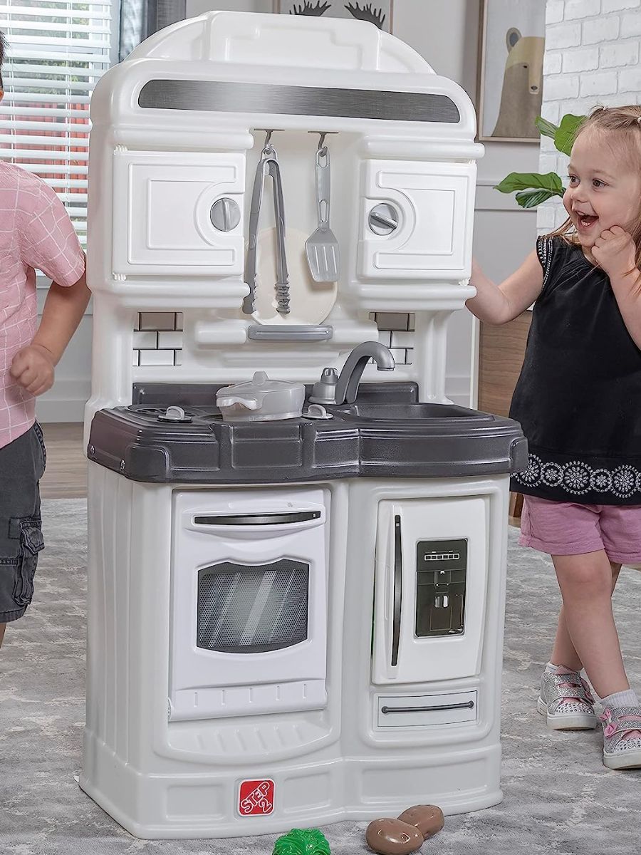 A play kitchen with two kids in it. 