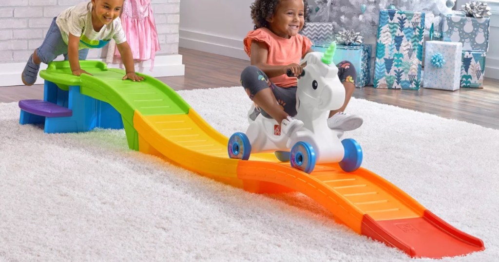 little girl riding Step2 Unicorn Up & Down Roller Coaster inside on carpet