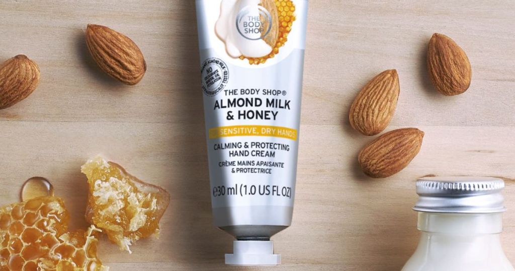 Body Shop milk and honey hand cream on a woooden counter with honeycomb and almonds