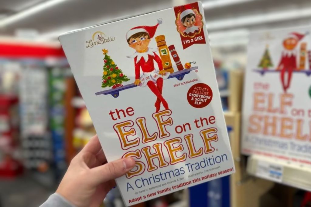 a mans hand holding The Elf on the Shelf boxed set