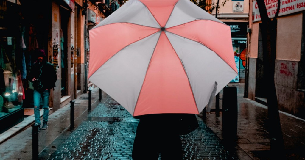 person walking down the street in the rain using an umbrella