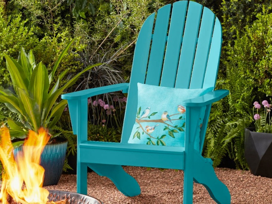 teal adirondack chair with throw pillow on patio near fire pit