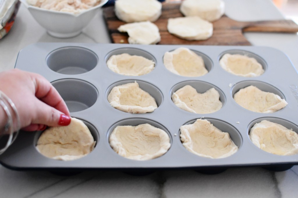 adding biscuit dough to muffin tin