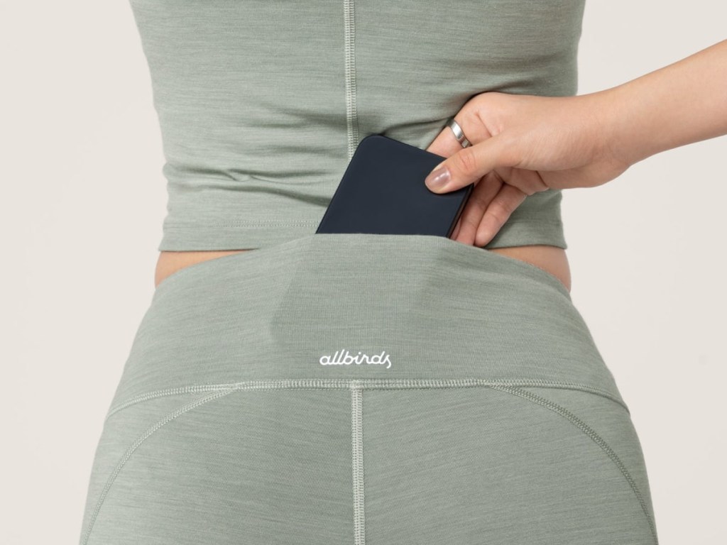 woman putting her phone into her allbirds leggings