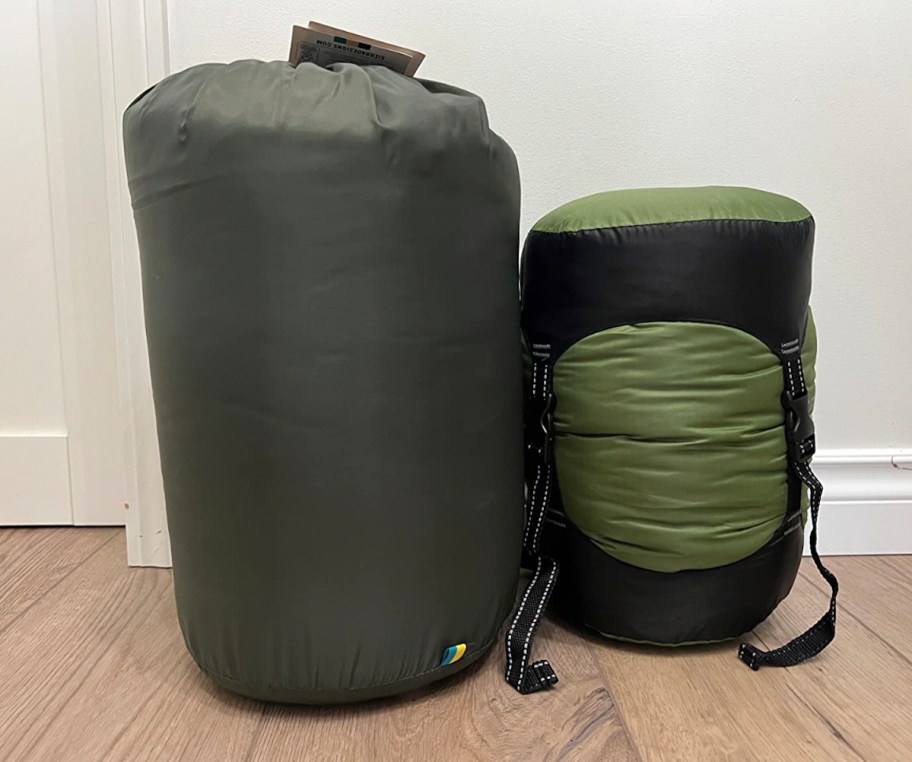 compression sacks with sleeping bags and clothes sitting on wood floor