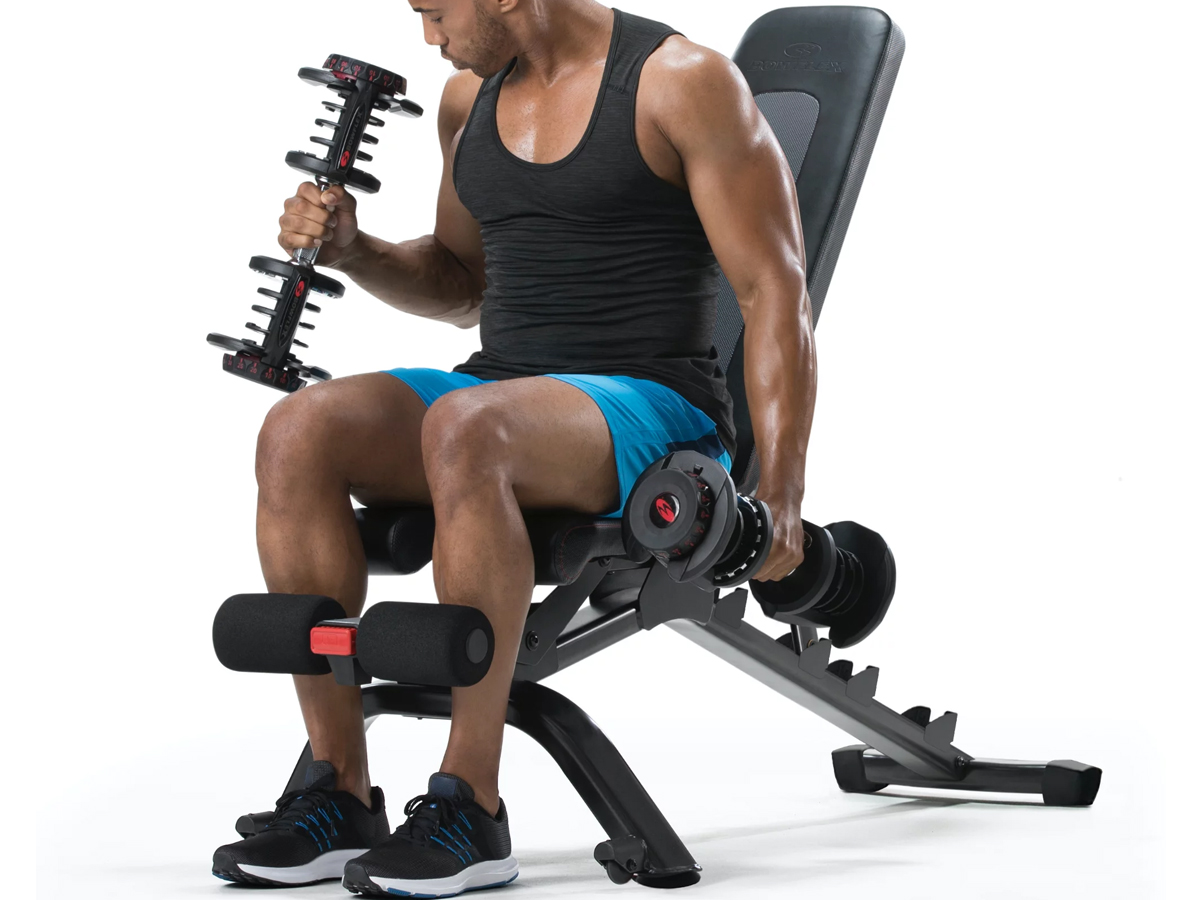 stock image of a man using a bowflex weight bench and weights