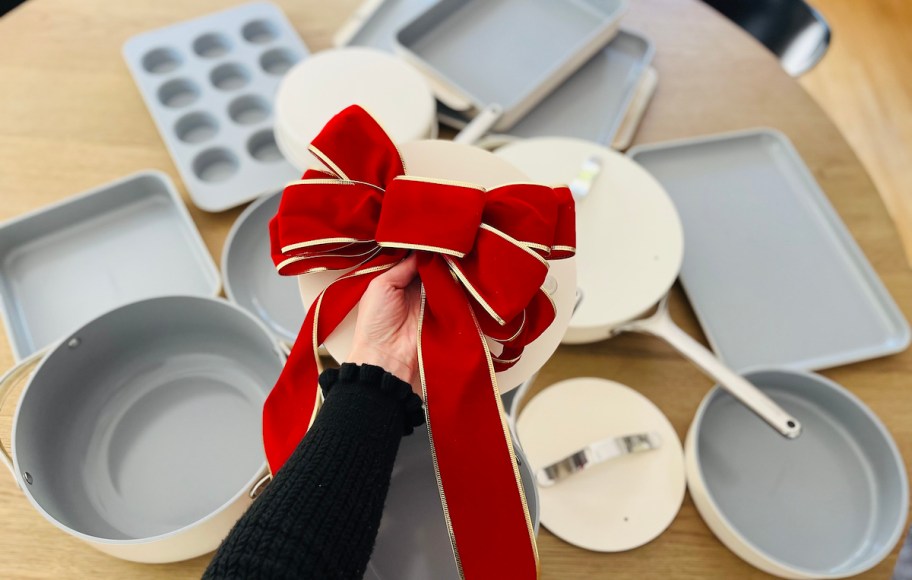 hand holding lid to stock pot with giant red bow