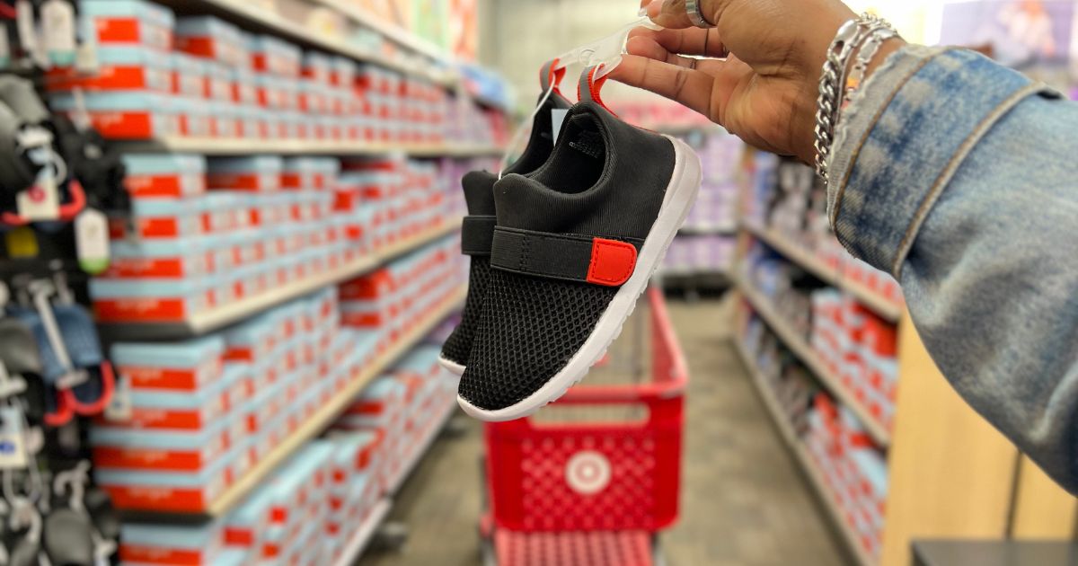 hand holding black and red pull on water shoes in store