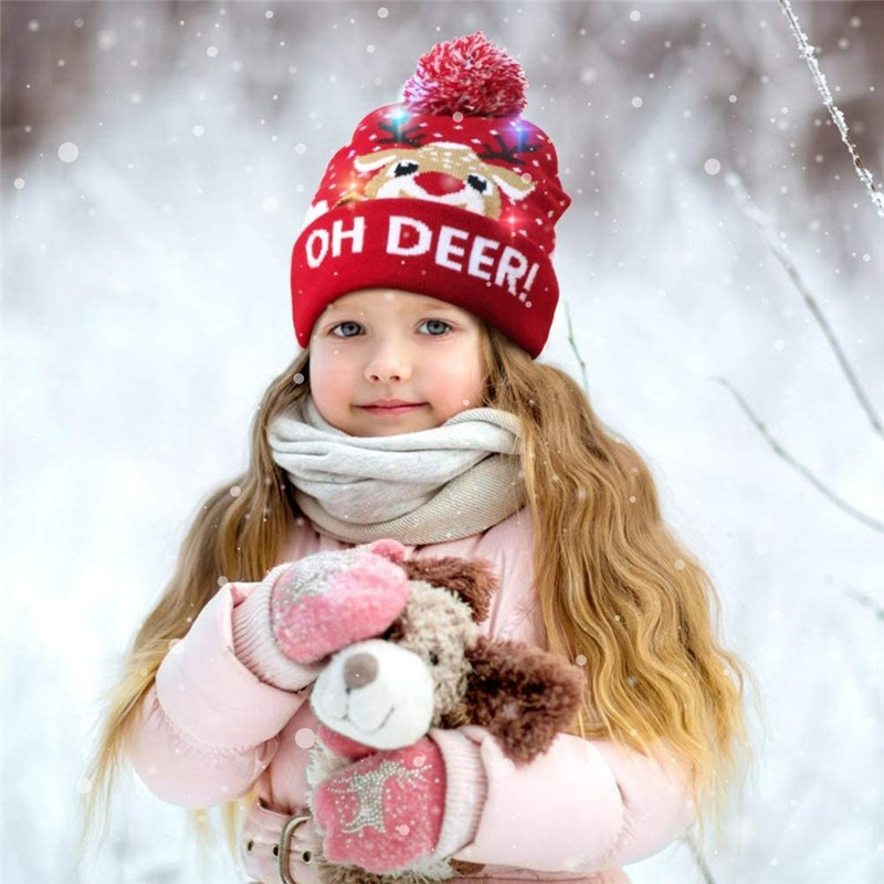 smiling girl holding a plush toy outside wearing a christmas led hat