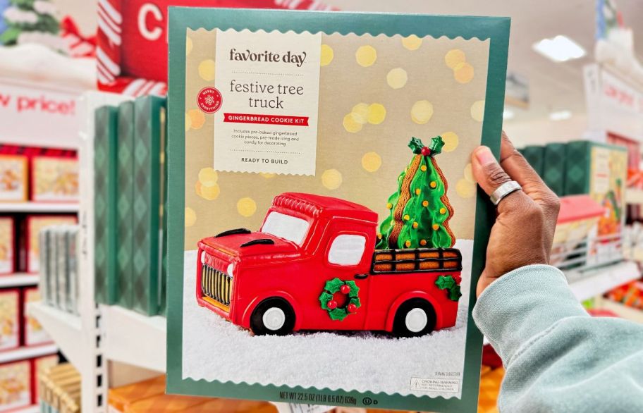 a womans hand holding a sugar cookie christmas truck decorating kit