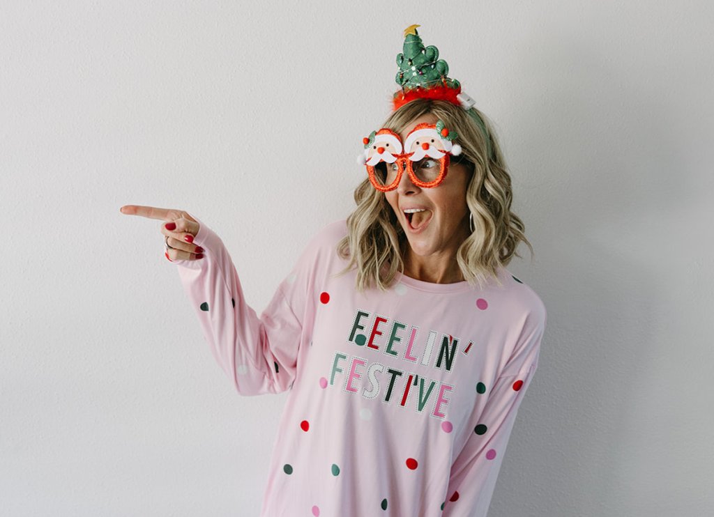 woman in pink pajamas wearing christmas glasses