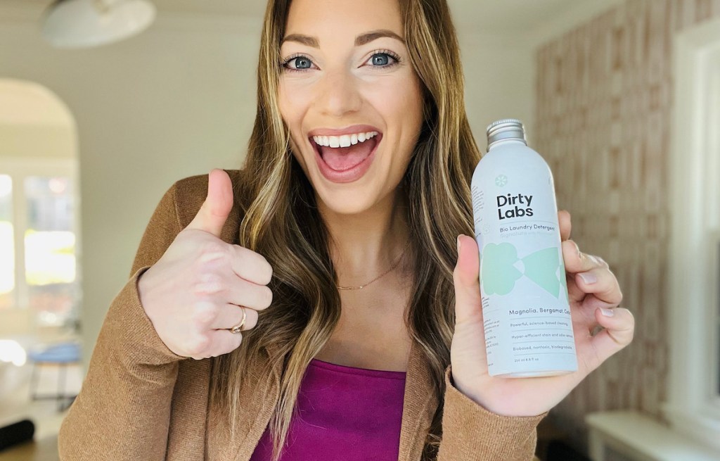 woman giving thumbs up holding bottle of household products