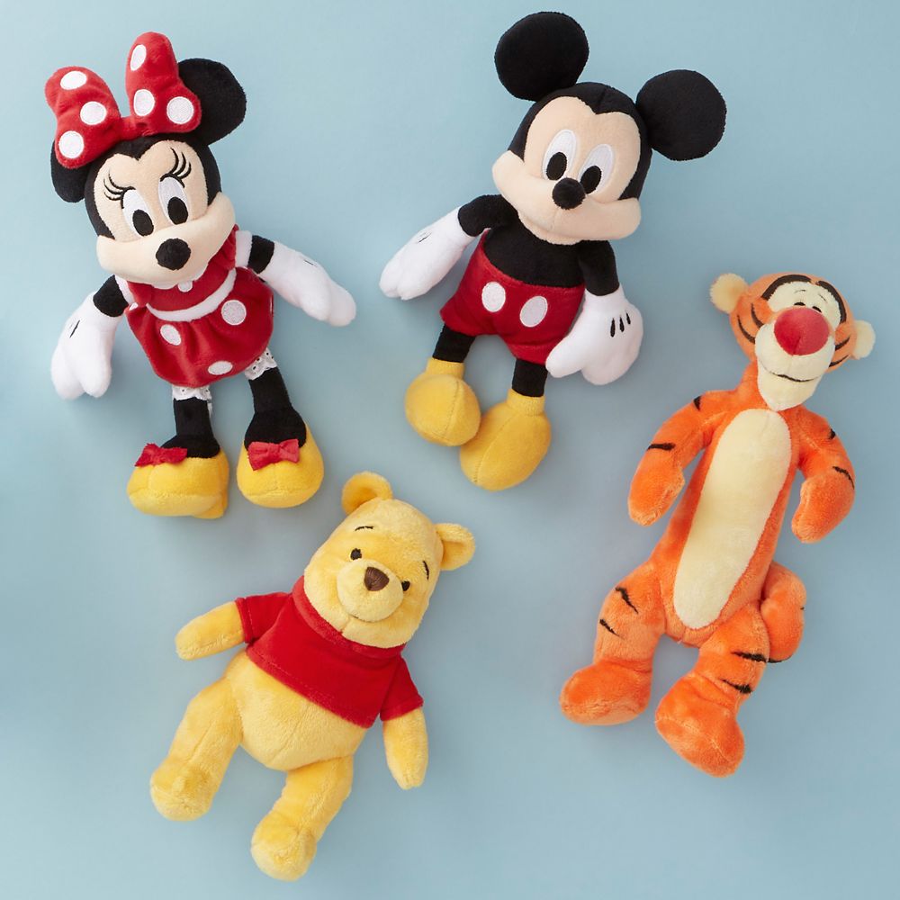 plush minnie mouse mickey mouse winnie the pooh and tigger toys against a slate blue background