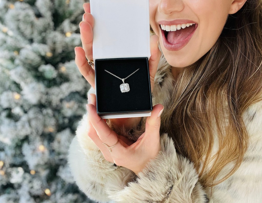 woman holding diamond necklace in front of christmas tree