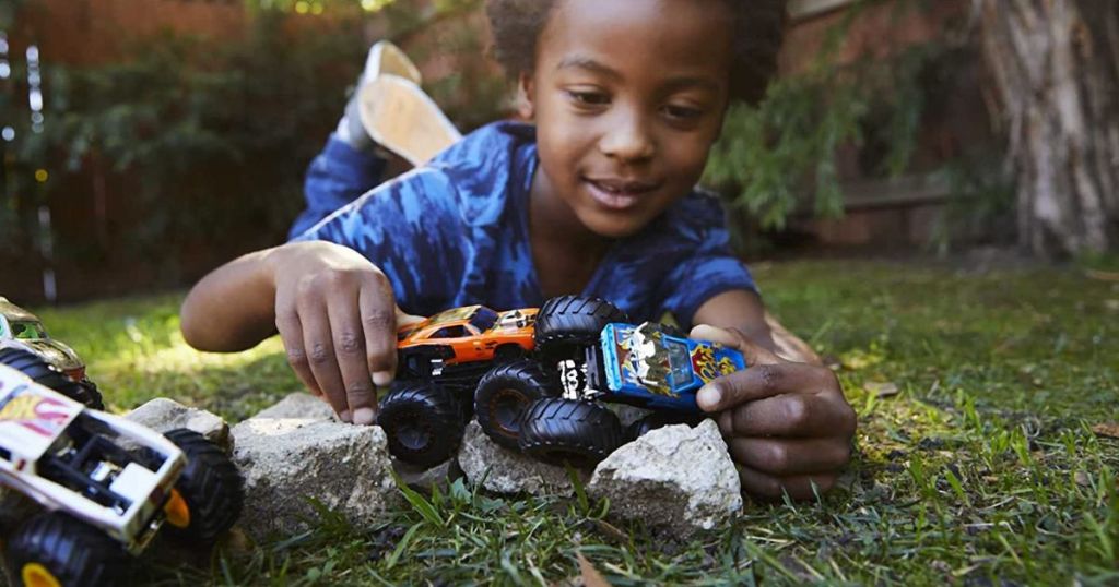kid playing with monster trucks in yard