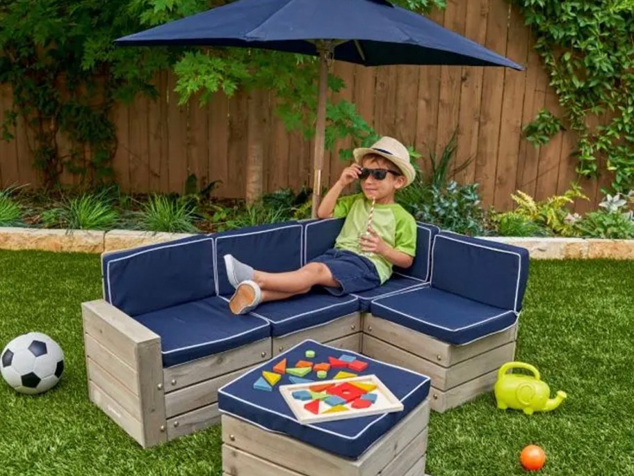 kid laying on blue kidcraft outdoor sectional