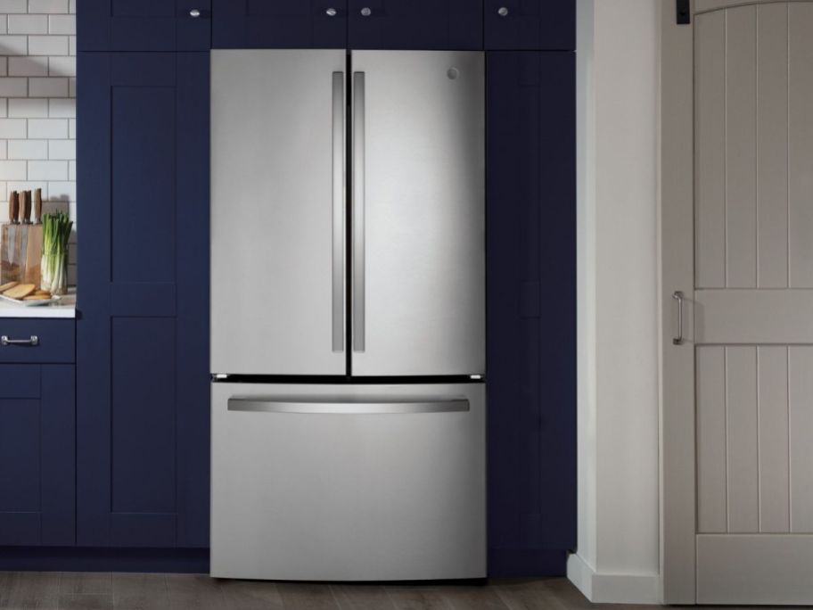 stainless steel refrigerator in kitchen with dark blue cabinets