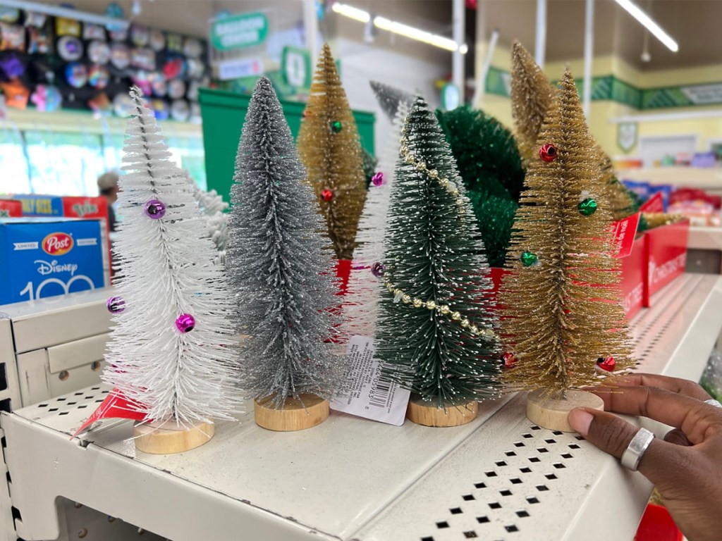 أشجار عيد الميلاد المصغرة مع الزخارف على الرف في شجرة الدولار