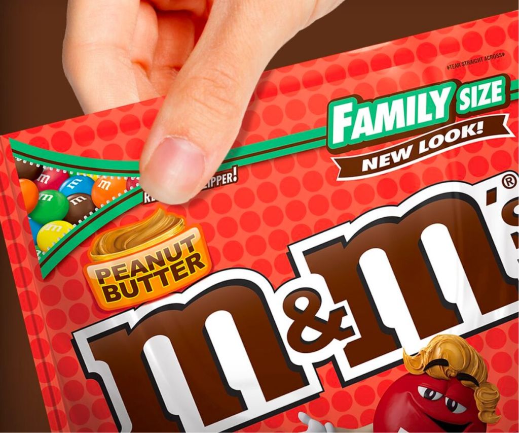 a finger and thumb pressing together the seal on a bag of family size m&m s with zip close