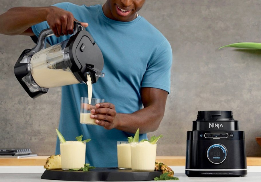 man pouring smoothie into cup with ninja blender pitcher