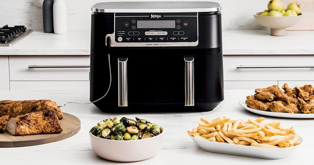 Ninja Foodi Air Fryer on counter with plates of food near it