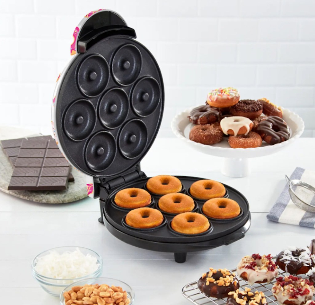 donut maker on counter with various decorated treats 