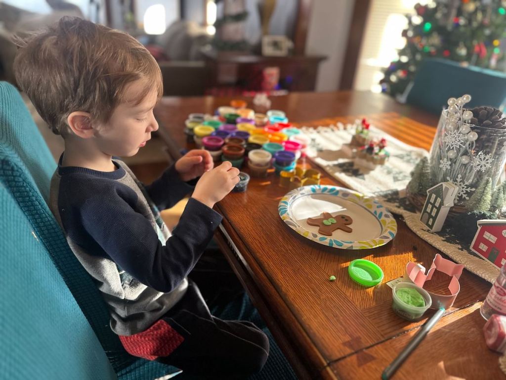 boy sitting at table playing with play doh set