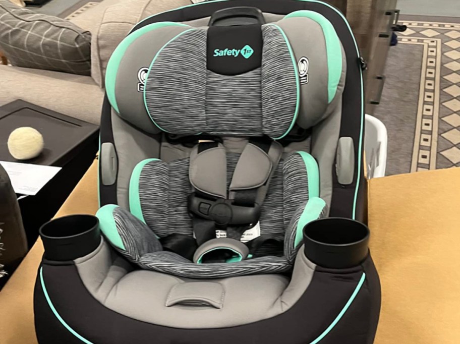 safety 1st car seat in grey and teal siting on a cardboard box on the floor of a home