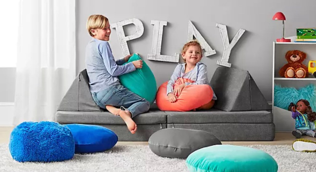 two kids playing on dark gray nugget lookalike sofa
