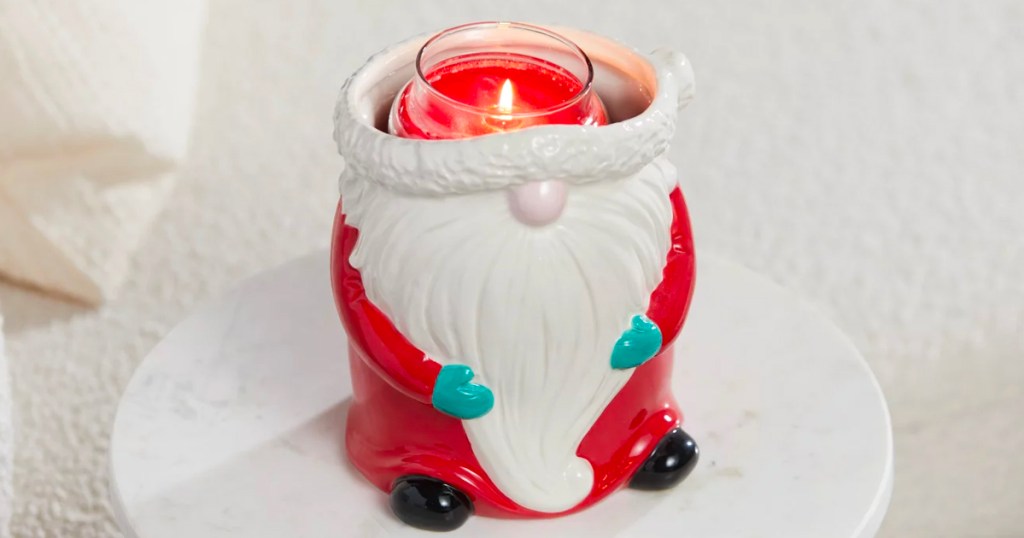 santa candle holder with red candle inside burning