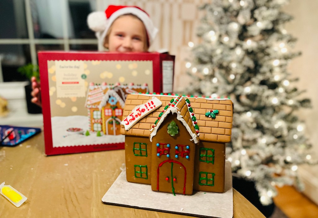 target favorite day holiday mansion gingerbread house on table with girl holding box