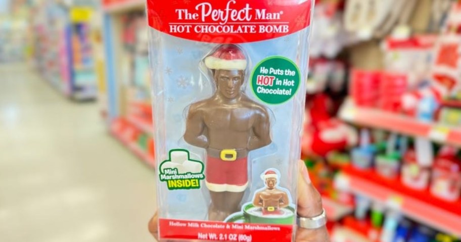 hand holding a box with a The Perfect Man Chocolate bomb in it that looks like a man with a Santa Hat and Shorts on