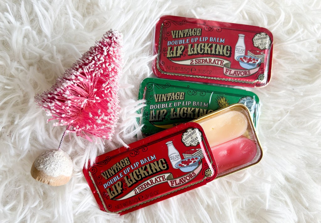 various tinte cosmetics duo lip balms on white fur rug with mini pink christmas tree