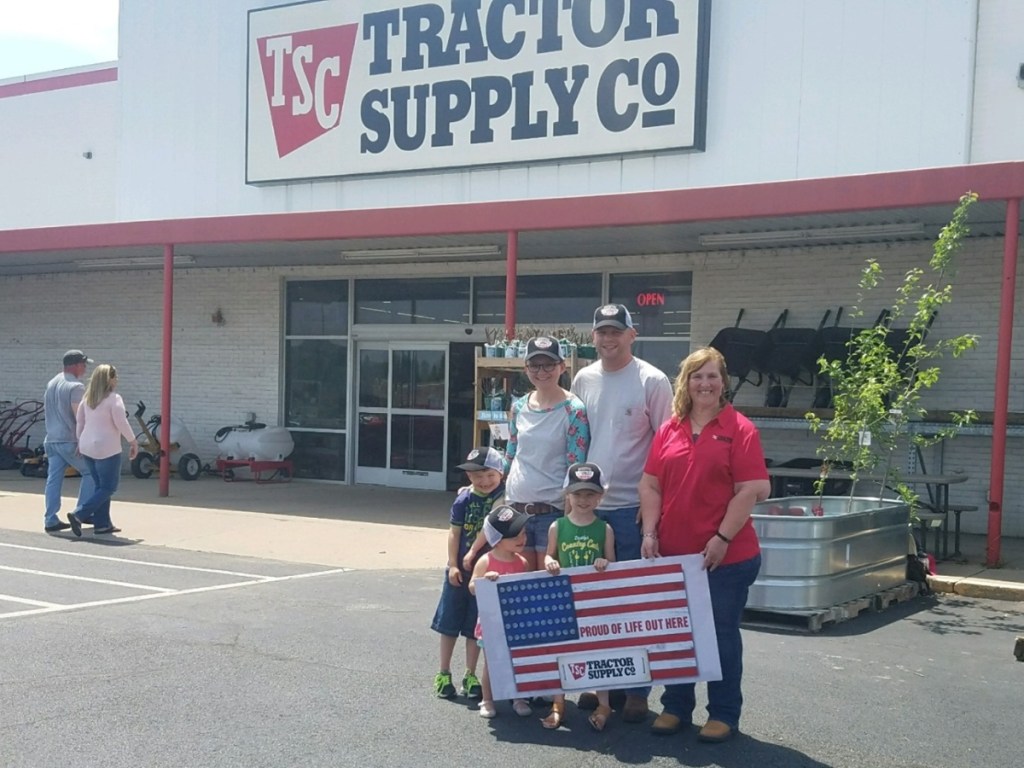 family with American flag sign outside Tractor Supply Co.