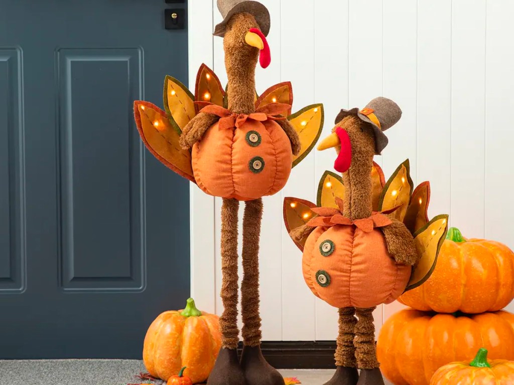 two turkey decor wearing pumpkins in front of door