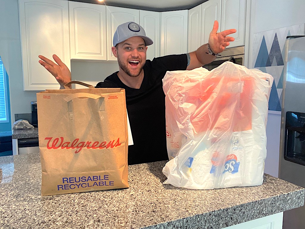 man standing by two Walgreens bags